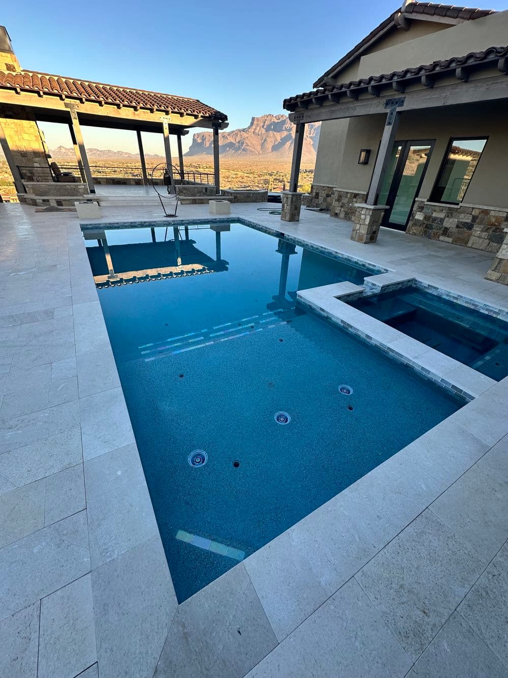 Luxury swimming pool with spa, mountain views, and modern patio design at sunset.